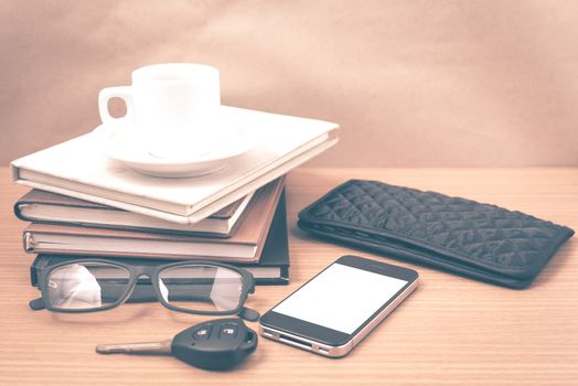 coffee and phone with stack of book,car key,eyeglasses and wallet on wood background vintage style