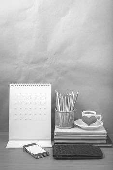 office desk : coffee with phone,wallet,calendar,heart,color pencil box,stack of book,heart on wood background black and white color