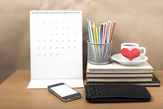 office desk : coffee with phone,wallet,calendar,heart,color pencil box,stack of book,heart on wood background