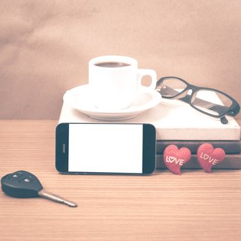 office desk : coffee and phone with car key,eyeglasses,stack of book,heart on wood background vintage style