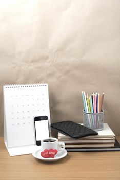 office desk : coffee with phone,wallet,calendar,heart,color pencil box,stack of book,heart on wood background