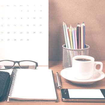 office desk : coffee with phone,wallet,calendar,heart,notepad,eyeglasses,color pencil box on wood background vintage style