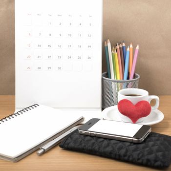 office desk : coffee with phone,wallet,calendar,heart,color pencil box,notepad,heart on wood background