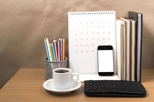 office desk : coffee with phone,wallet,calendar,color pencil box,stack of book on wood background