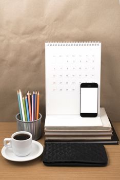 office desk : coffee with phone,wallet,calendar,color pencil box,stack of book on wood background