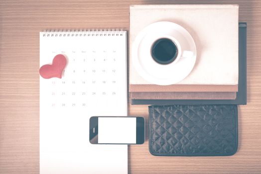 office desk : coffee with phone,wallet,calendar,heart,stack of book on wood background vintage style