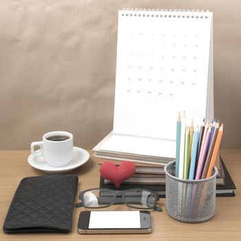 office desk : coffee with phone,wallet,calendar,color pencil box,stack of book,heart,eyeglasses on wood background