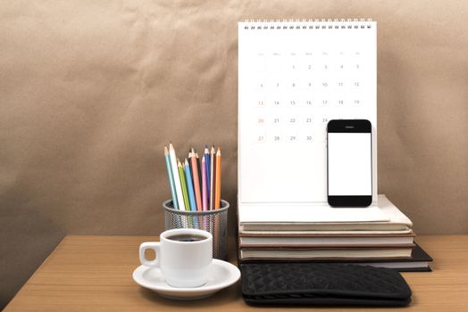 office desk : coffee with phone,wallet,calendar,color pencil box,stack of book on wood background