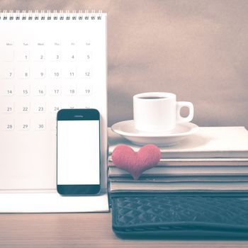 office desk : coffee with phone,wallet,calendar,heart,stack of book on wood background vintage style