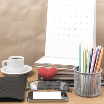 office desk : coffee with phone,wallet,calendar,color pencil box,stack of book,heart,eyeglasses on wood background
