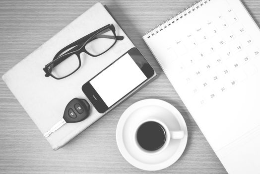 coffee and phone with car key,eyeglasses,stack of book,calendar on wood background black and white color