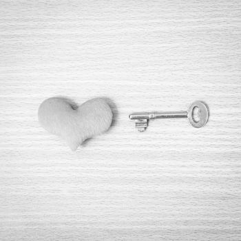 red heart with key on wood table background black and white color