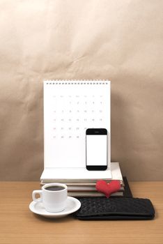 office desk : coffee with phone,wallet,calendar,heart,stack of book on wood background