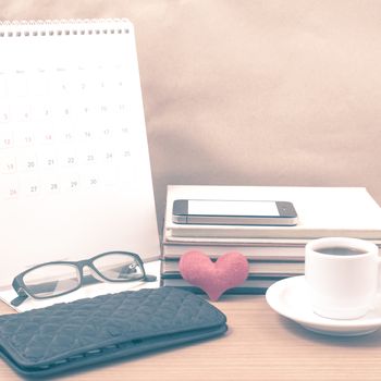 desktop : coffee with phone,stack of book,wallet,heart,eyeglasses,calendar on wood background vintage style