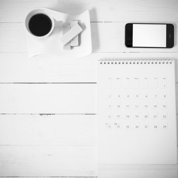 coffee cup with wafer,phone,calendar on white wood background black and white color