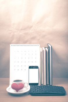 office desk : coffee with phone,wallet,calendar,heart,stack of book on wood background vintage style