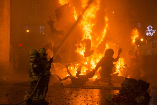 SPAIN, Valencia : Firefighters attempt to extinguish fire as ninots burn on the last night of the Fallas Festival in Valencia on March 19, 2016.Fallas are gigantic structures made of cardboard portraying current events and personalities in which individual figures or Ninots are placed. The Fallas are burnt in the streets of Valencia as a tribute to St Joseph, patron saint of the carpenters' guild. 