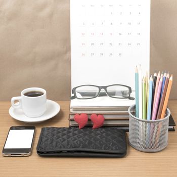 office desk : coffee with phone,wallet,calendar,color pencil box,stack of book,heart,eyeglasses on wood background