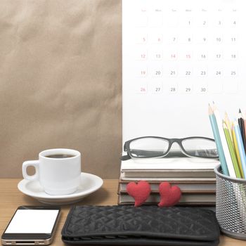 office desk : coffee with phone,wallet,calendar,color pencil box,stack of book,heart,eyeglasses on wood background