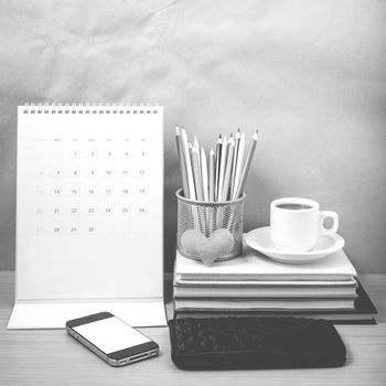 office desk : coffee with phone,wallet,calendar,heart,color pencil box,stack of book,heart on wood background black and white color