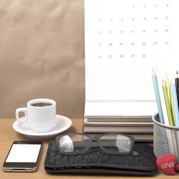 office desk : coffee with phone,wallet,calendar,color pencil box,stack of book,heart,eyeglasses on wood background