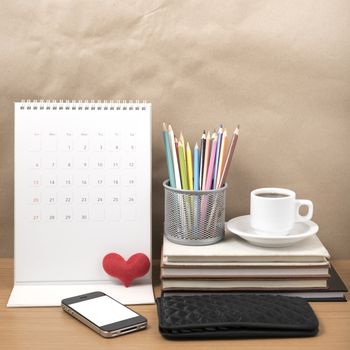 office desk : coffee with phone,wallet,calendar,heart,color pencil box,stack of book,heart on wood background