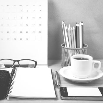 office desk : coffee with phone,wallet,calendar,heart,notepad,eyeglasses,color pencil box on wood background black and white color