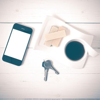 coffee cup with wafer,phone,key on white wood background vintage style