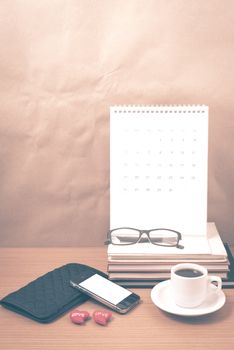 office desk : coffee with phone,wallet,calendar,heart,stack of book,eyeglasses on wood background vintage style
