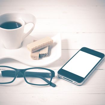 coffee cup with wafer,phone,eyeglasses on white wood background vintage style
