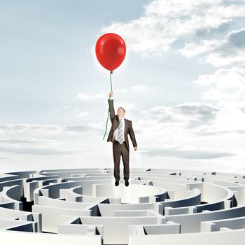 Businessman flying up with red balloon above labyrinth