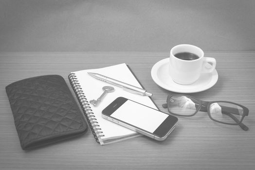 coffee and phone with notepad,key,eyeglasses and wallet on wood table background black and white color