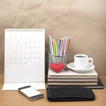 office desk : coffee with phone,wallet,calendar,heart,color pencil box,stack of book,heart on wood background