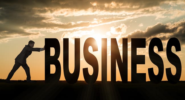 Businessman pushing word business on sunset background