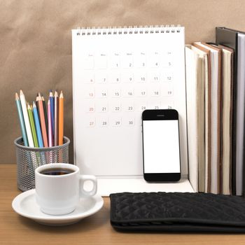 office desk : coffee with phone,wallet,calendar,color pencil box,stack of book on wood background