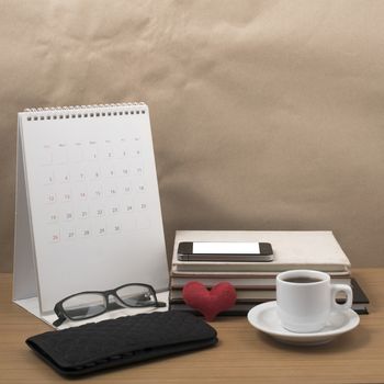 desktop : coffee with phone,stack of book,wallet,heart,eyeglasses,calendar on wood background