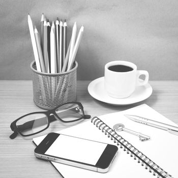 office desk : coffee and phone with key,eyeglasses,notepad,pencil box black and white color