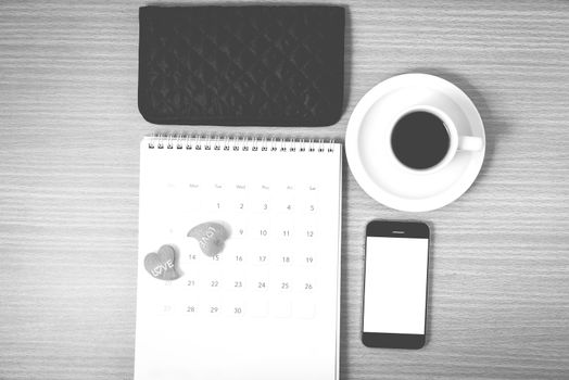office desk : coffee with phone,calendar,wallet,heart on wood background black and white color