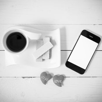 coffee cup with wafer,phone,heart on white wood background black and white color