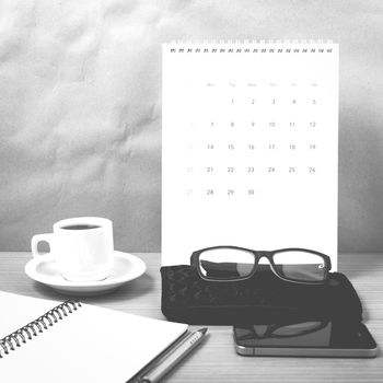 office desk : coffee with phone,calendar,wallet,notepad on wood background black and white color
