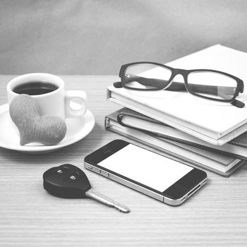 office desk : coffee and phone with car key,eyeglasses,stack of book,heart black and white color
