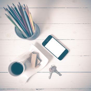 coffee cup with wafer,phone,pencil box,key on white wood background vintage style