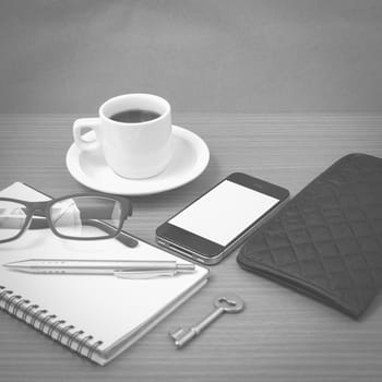 coffee and phone with notepad,key,eyeglasses and wallet on wood table background black and white color