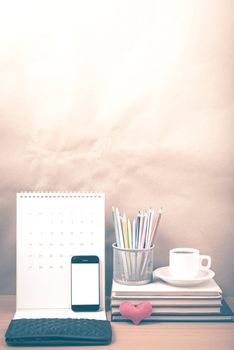 office desk : coffee with phone,wallet,calendar,heart,color pencil box,stack of book,heart on wood background vintage style