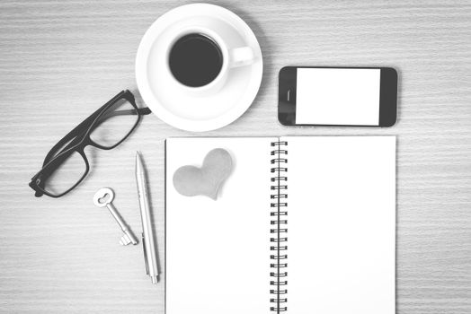 office desk : coffee and phone with key,eyeglasses,notepad,heart on wood background black and white color