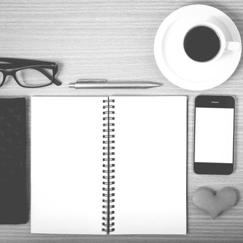 office desk : coffee with phone,notepad,eyeglasses,wallet,heart on wood background black and white color