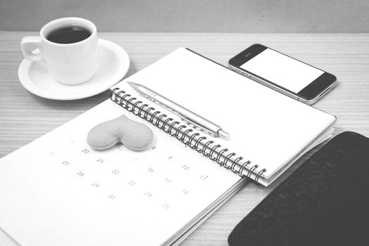 office desk : coffee with phone,wallet,calendar,heart,notepad on wood background black and white color