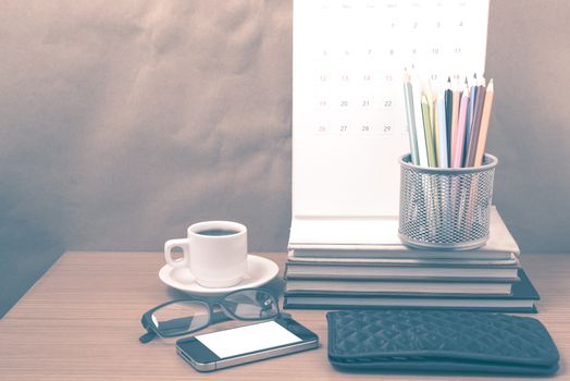 office desk : coffee with phone,wallet,calendar,color pencil box,stack of book,eyeglasses on wood background vintage style