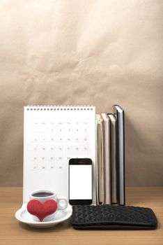office desk : coffee with phone,wallet,calendar,heart,stack of book on wood background