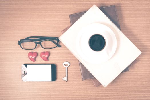 office desk : coffee and phone with key,eyeglasses,stack of book,heart on wood background vintage style